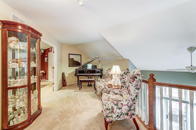 sitting room with ceiling fan, light colored carpet, and vaulted ceiling