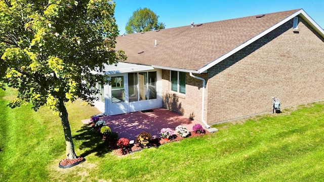 rear view of house with a sunroom, a yard, and a patio