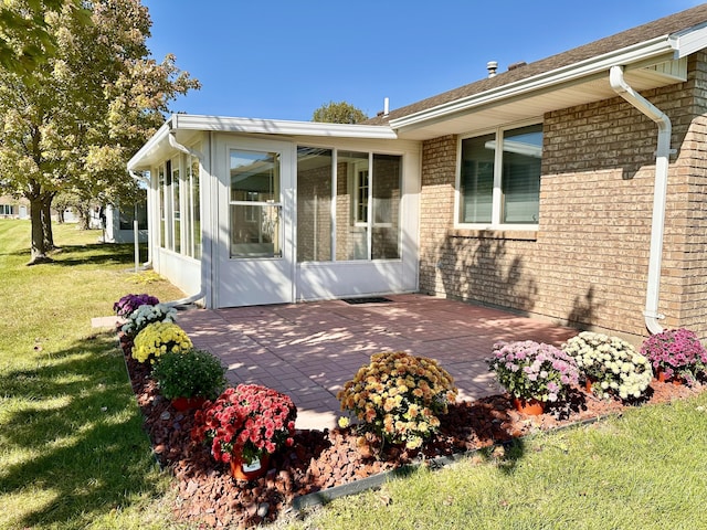 exterior space featuring a lawn, a sunroom, and a patio