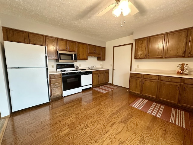 kitchen featuring ceiling fan, sink, light hardwood / wood-style flooring, a textured ceiling, and white appliances