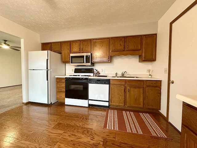 kitchen with a textured ceiling, ceiling fan, sink, and white appliances