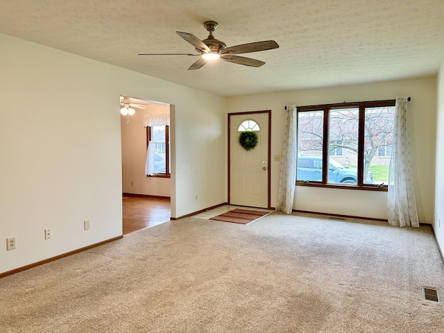 entrance foyer featuring light carpet, a textured ceiling, and ceiling fan