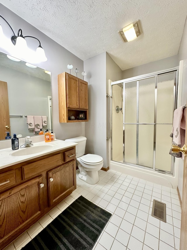 bathroom with vanity, a textured ceiling, tile patterned floors, and a shower with shower door