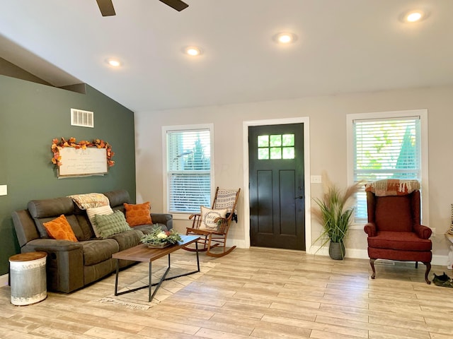 living room featuring a healthy amount of sunlight, lofted ceiling, and light hardwood / wood-style flooring