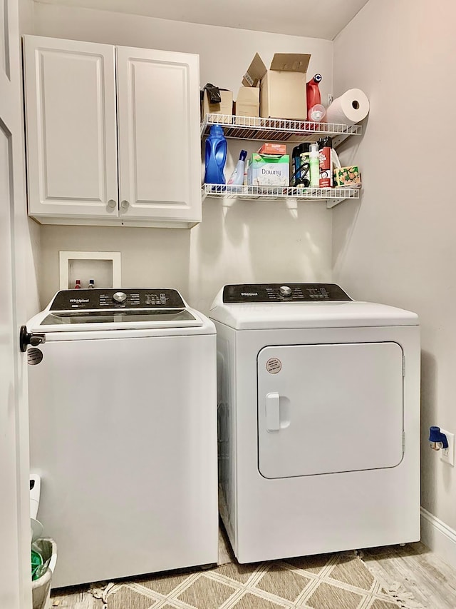 laundry area featuring washer and dryer, cabinets, and light hardwood / wood-style flooring