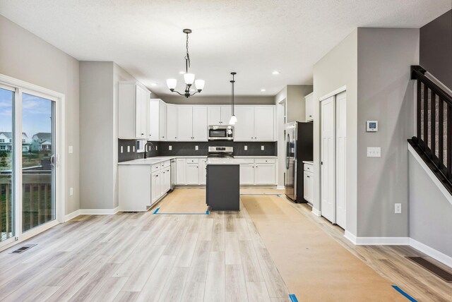 kitchen featuring a center island, hanging light fixtures, stainless steel appliances, light hardwood / wood-style floors, and white cabinets