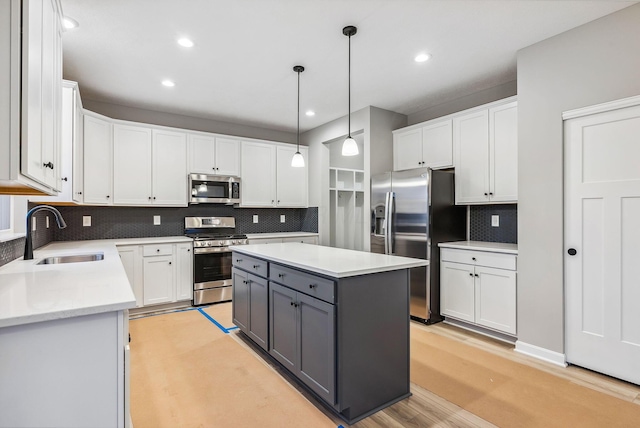 kitchen featuring sink, stainless steel appliances, a kitchen island, backsplash, and white cabinets