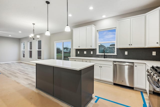 kitchen featuring white cabinets, decorative light fixtures, stainless steel appliances, and sink