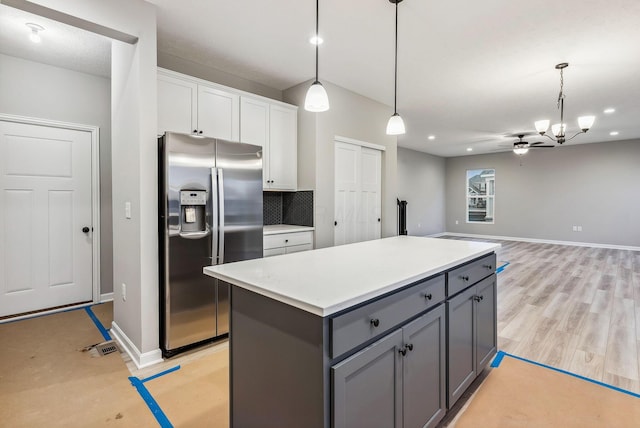 kitchen featuring ceiling fan with notable chandelier, decorative light fixtures, white cabinets, stainless steel fridge with ice dispenser, and a kitchen island