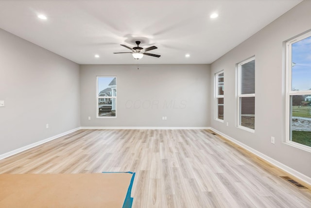 empty room with ceiling fan, a healthy amount of sunlight, and light hardwood / wood-style floors