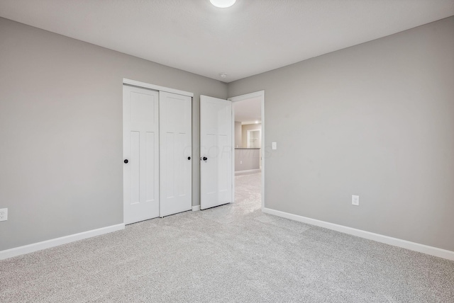 unfurnished bedroom featuring a closet and light colored carpet