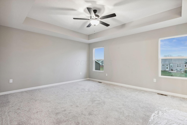 carpeted empty room with a tray ceiling and ceiling fan