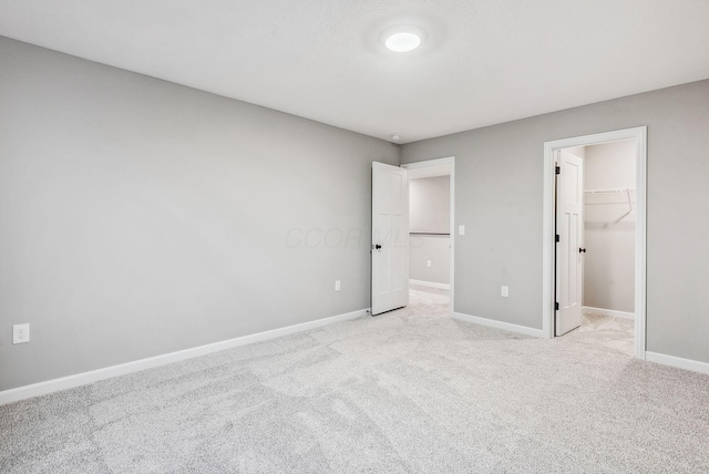 unfurnished bedroom with light carpet, a walk in closet, and a closet