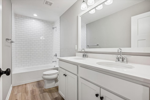 full bathroom featuring hardwood / wood-style flooring, vanity, toilet, and tiled shower / bath