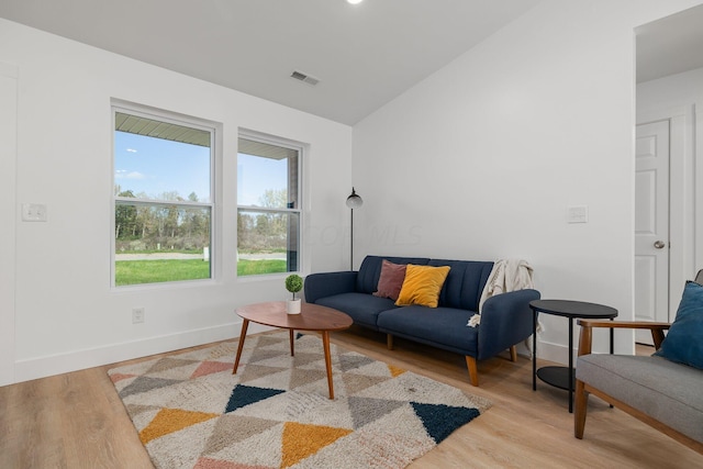 living room with light wood-type flooring and vaulted ceiling