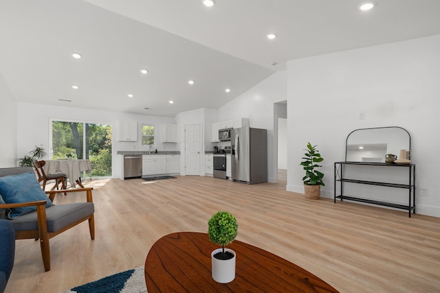 living room featuring light hardwood / wood-style flooring, high vaulted ceiling, and sink