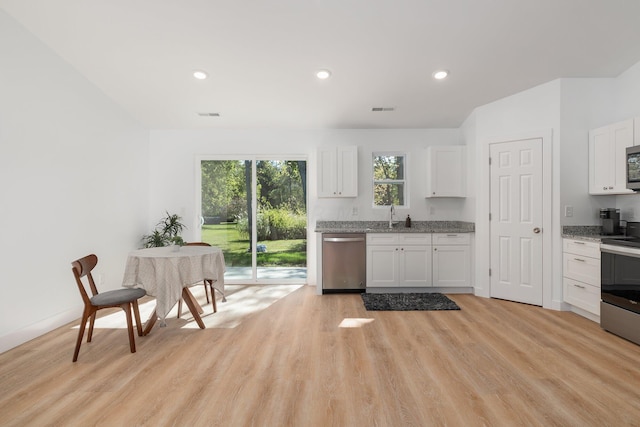 kitchen featuring light stone countertops, stainless steel appliances, sink, white cabinets, and light hardwood / wood-style floors