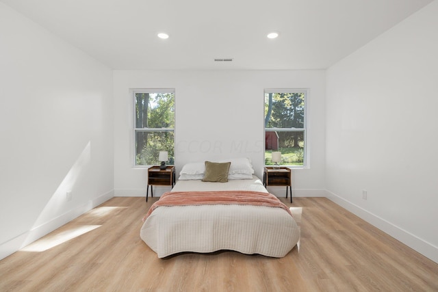 bedroom with light wood-type flooring and multiple windows