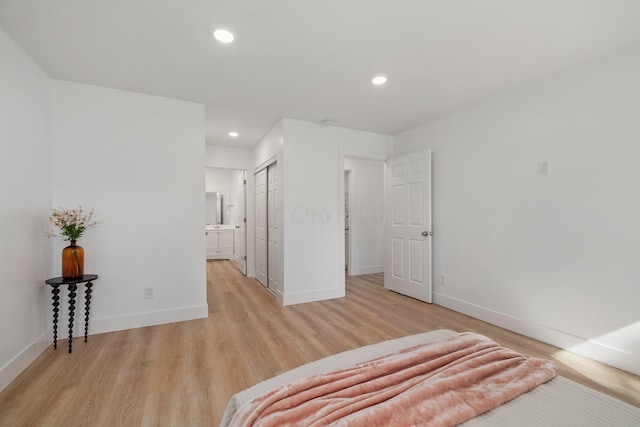 bedroom with ensuite bathroom, a closet, and light hardwood / wood-style floors