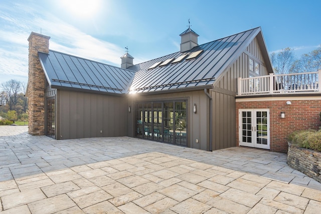 back of property featuring french doors, a balcony, and a patio