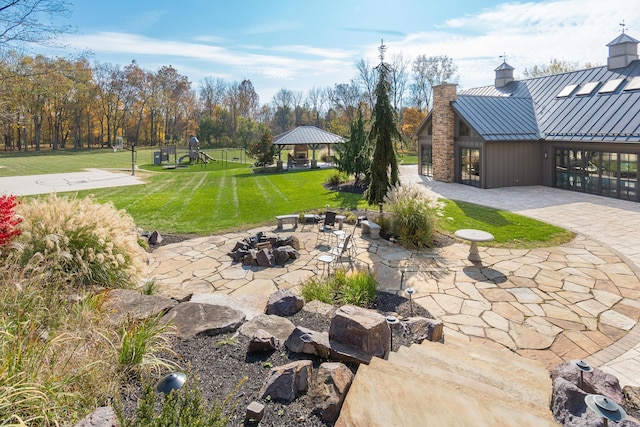 view of yard featuring a gazebo, a patio, a playground, and an outdoor fire pit