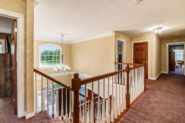 hall with carpet flooring, a notable chandelier, crown molding, and a textured ceiling