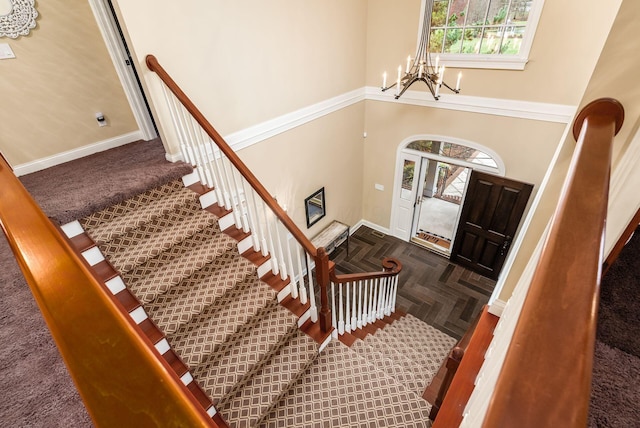 foyer entrance featuring a wealth of natural light, an inviting chandelier, and parquet flooring