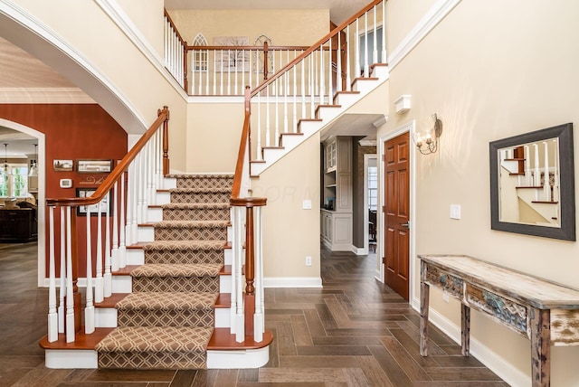 entryway featuring a high ceiling, dark parquet floors, and ornamental molding