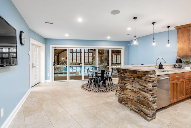 kitchen featuring plenty of natural light, sink, stainless steel dishwasher, and decorative light fixtures