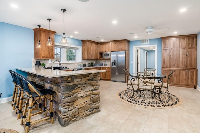 kitchen featuring sink, hanging light fixtures, stainless steel appliances, backsplash, and kitchen peninsula