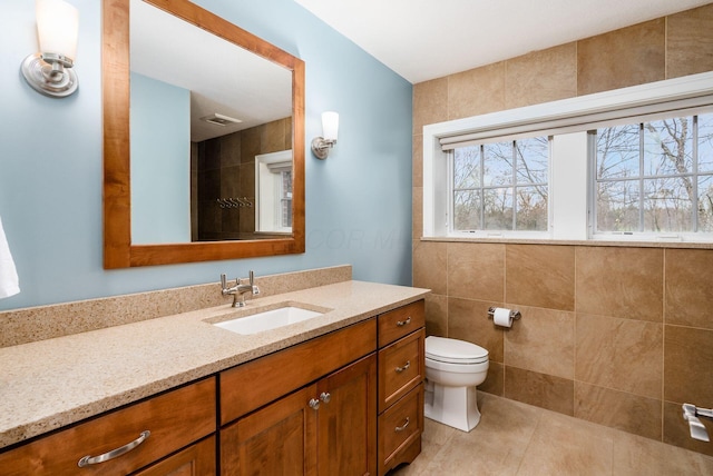 bathroom featuring tile patterned floors, vanity, tile walls, and toilet