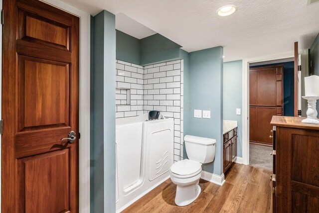 bathroom with vanity, a bathing tub, toilet, a textured ceiling, and wood-type flooring