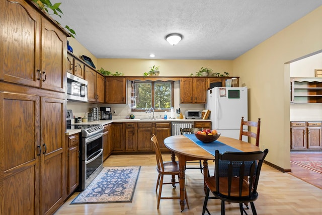 kitchen featuring a textured ceiling, stainless steel appliances, light hardwood / wood-style floors, and sink