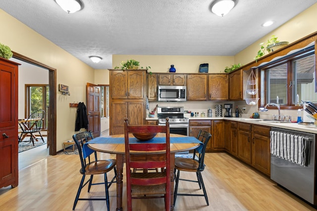 kitchen featuring sink, light hardwood / wood-style flooring, a textured ceiling, and appliances with stainless steel finishes