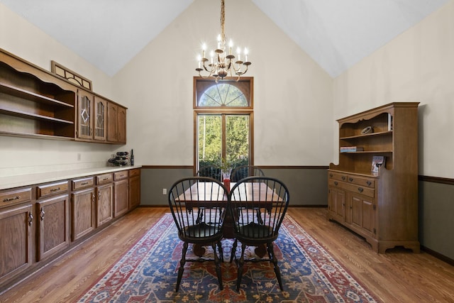 dining room with high vaulted ceiling, light hardwood / wood-style floors, and an inviting chandelier