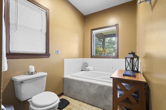 bathroom with toilet and tiled bath