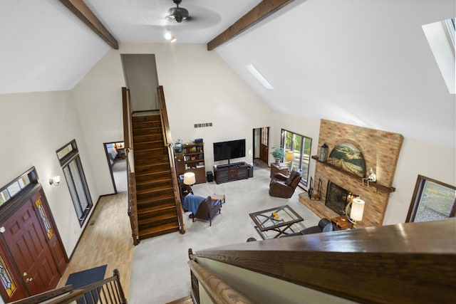 living room featuring beam ceiling, ceiling fan, a large fireplace, high vaulted ceiling, and wood-type flooring