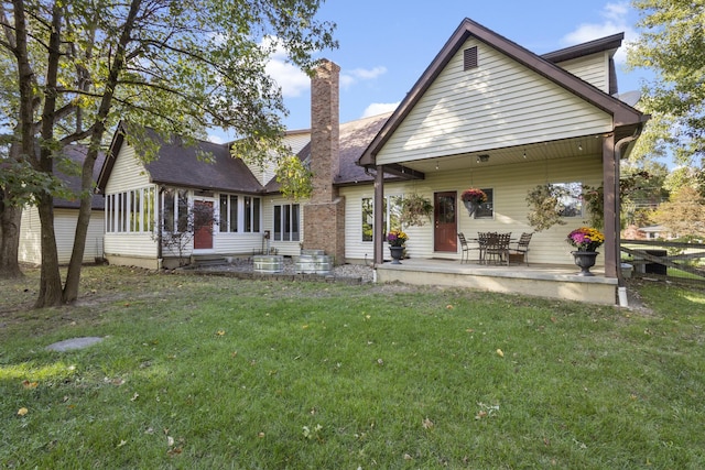 rear view of house featuring a lawn and a sunroom