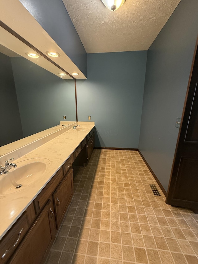 bathroom with visible vents, a sink, a textured ceiling, and double vanity