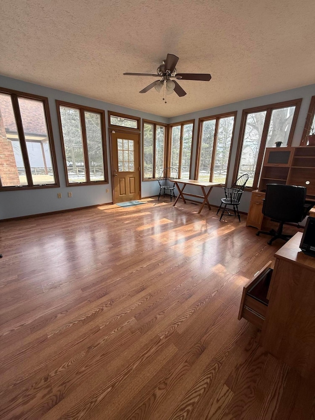unfurnished sunroom featuring a ceiling fan