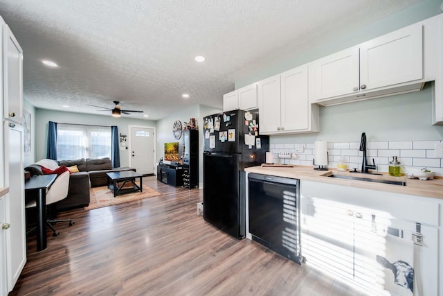 kitchen featuring sink, white cabinets, black appliances, and wood-type flooring