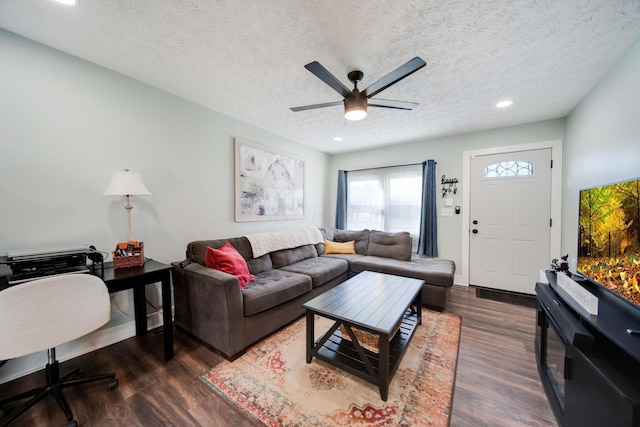 living room featuring a textured ceiling, ceiling fan, and dark wood-type flooring