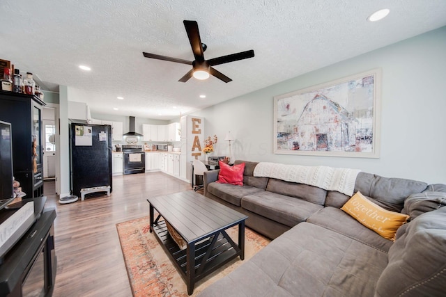 living room with ceiling fan, light hardwood / wood-style floors, and a textured ceiling