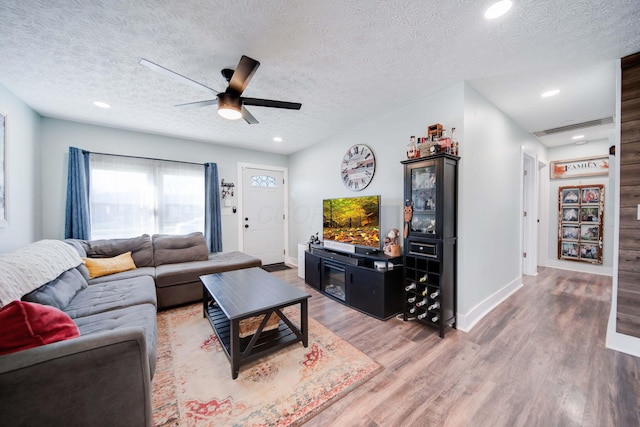 living room featuring ceiling fan, hardwood / wood-style floors, and a textured ceiling