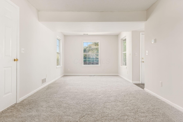 empty room with baseboards, visible vents, and carpet flooring