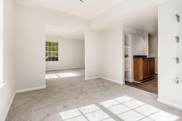 carpeted spare room featuring baseboards