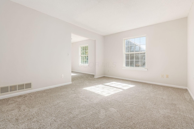 carpeted empty room with visible vents and baseboards