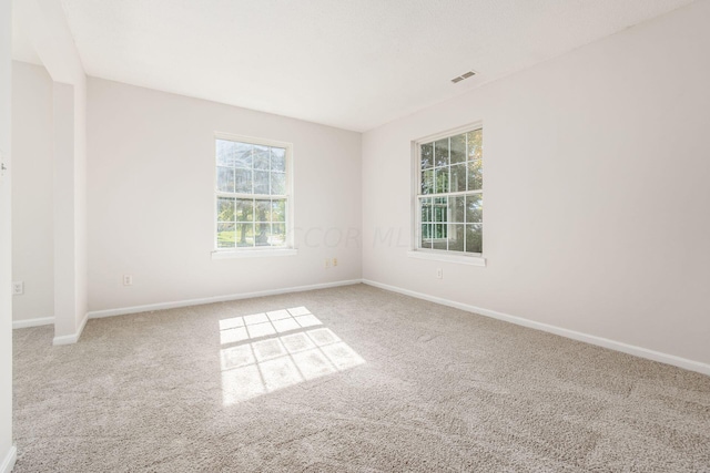 carpeted spare room featuring visible vents and baseboards