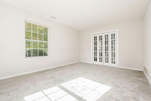 carpeted spare room featuring baseboards and visible vents