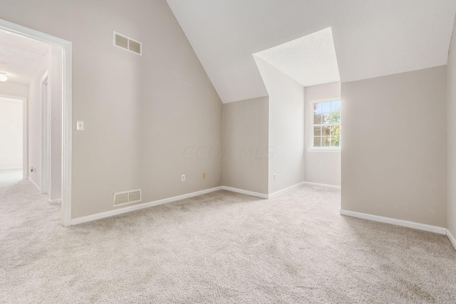 additional living space featuring lofted ceiling, carpet flooring, and visible vents